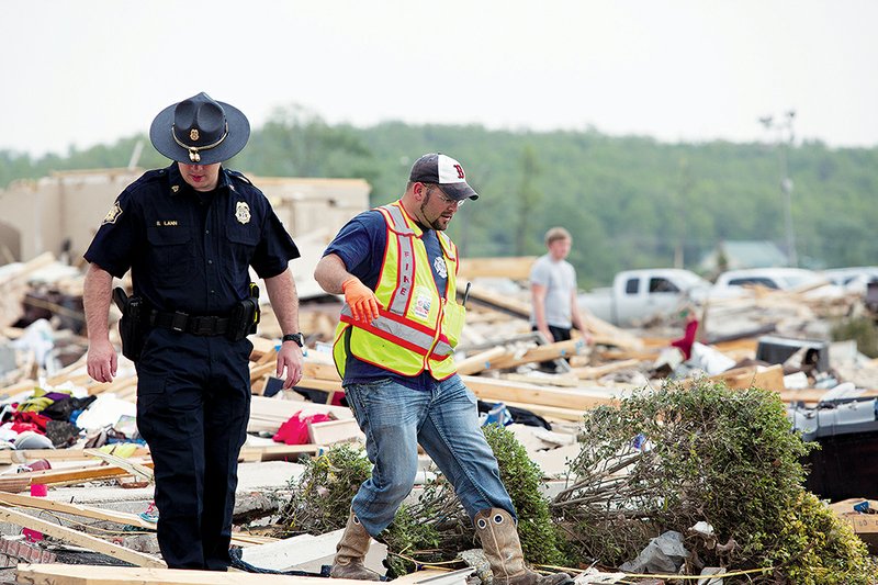 Law enforcement officers and volunteers, such as these in Vilonia, looked through the rubble after Sunday night’s tornado that killed eight people and hospitalized at least nine others in the community, one of whom was in critical condition at press time.