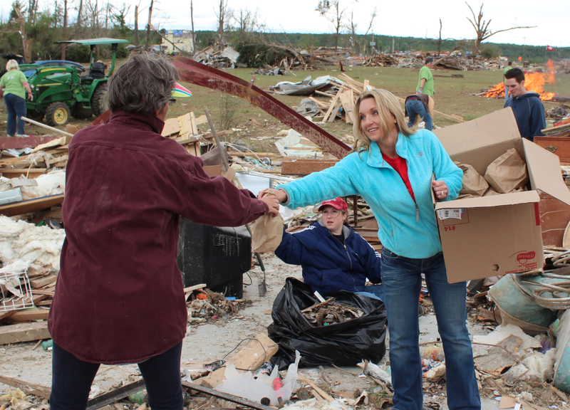 Maree Coats, right, hands out lunch at a destroyed home along Cemetery Road Wednesday in Vilonia.