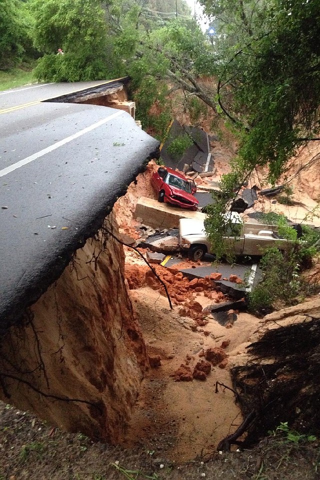 Vehicles sit amid collapsed pavement Wednesday after heavy rains washed a segment of a scenic highway into a ravine near Pensacola, Fla. 