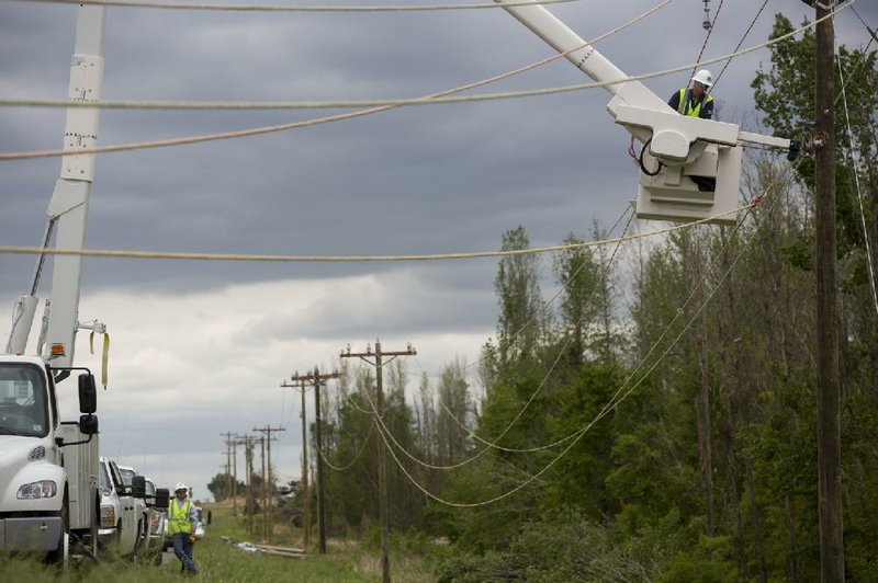 Journeyman technician Grant Pugh of BBC Electric hangs rope to new poles to guide the stringing of power lines Wednesday in Mayflower where Sunday’s tornado tore out the lines. 