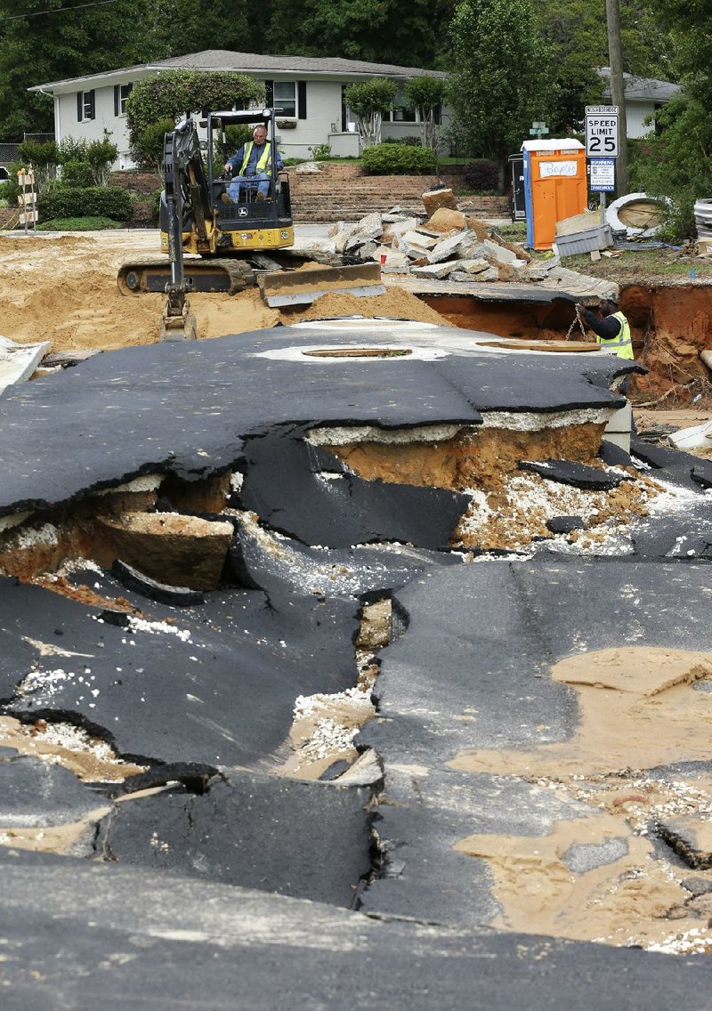 Workers repair a street Thursday that was washed out in this week’s flooding in Pensacola, Fla. 