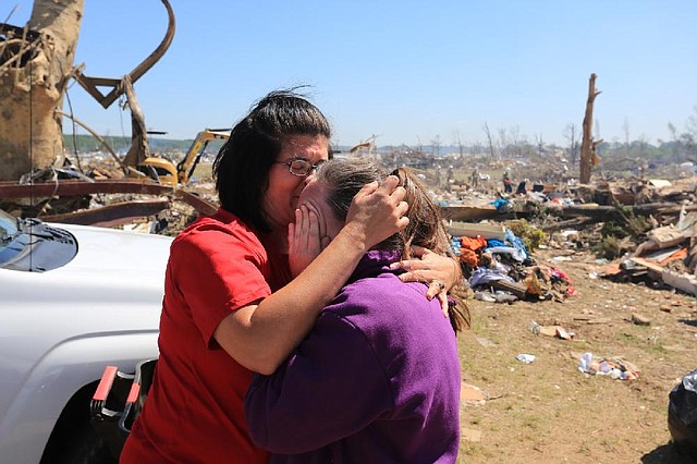 Carrie Smith (left) of Judsonia hugs her friend Melissa Bradley near the remains of Bradley’s home Thursday on Cemetery Road in Vilonia. Bradley’s 13-year-old daughter and a 16-year-old baby sitter survived Sunday’s tornado huddling in a closet. 