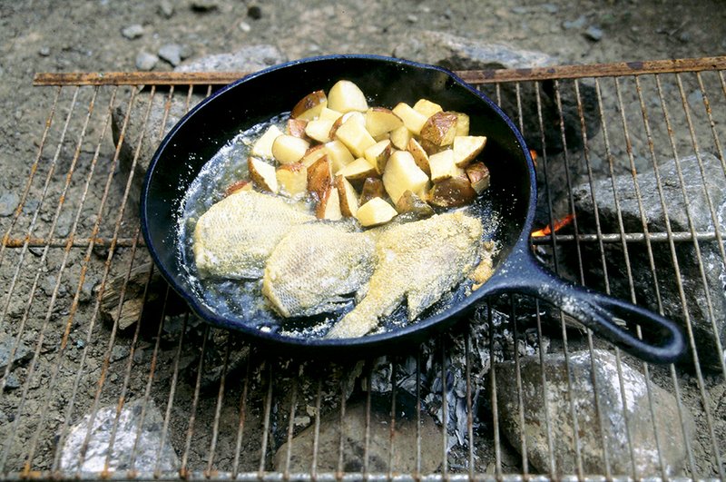 A few potatoes and onions can be cooked right in the skillet with fish for a delicious meal outdoors.