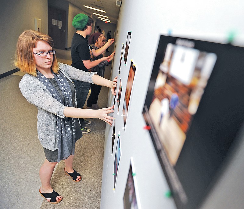 STAFF PHOTO ANDY SHUPE Paxton Douglas, 19, a senior, works Thursday hanging photographs in the &#8220;Community Through Photography&#8221; exhibit in the halls of Fayetteville High School. The exhibit is a product of the Adopt-A-Classroom effort, a partnership between high school sociology students and students in the University of Arkansas&#8217; Department of Sociology and Criminal Justice.