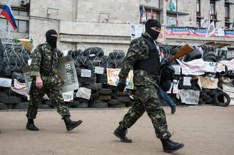 Pro-Russian activists walk by a barricade at the regional administration building in Donetsk, Ukraine, Friday, May 2, 2014. Ukraine launched what appeared to be its first major assault against pro-Russian forces who have seized government buildings in the country's east, with fighting breaking out Friday in Slovyansk that has become the focus of the insurgency.