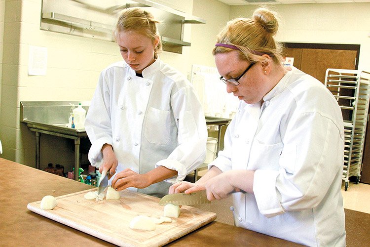 From left, Sierra Wood and Molly-Anne Kirby chop onions in the Beebe School District’s Career and Technical Center. Beebe Superintendent Belinda Shook said she hopes students and teachers in the Career and Technical programs will be able to help at the new food pantry that will open next school year.