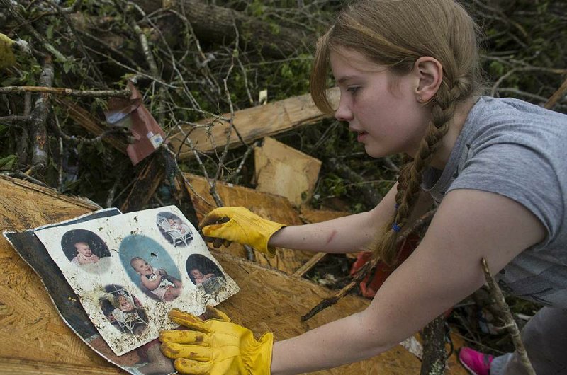 Emily Tittle collects photos outside her family’s home in western Pulaski County, where her father and two of her sisters were killed in last Sunday’s tornado. 