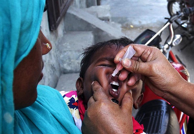 A Pakistani health worker gives a child a polio vaccine in Lahore, Pakistan, Monday, May 5, 2014. For the first time, the World Health Organization on Monday declared the spread of polio an international public health emergency that could grow in the next few months and unravel the nearly three-decade effort to eradicate the crippling disease. (AP Photo/K.M. Chaudary)