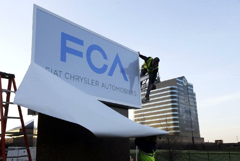 A worker unveils a new Fiat Chrysler Automobiles sign Tuesday at Chrysler World Headquarters in Auburn Hills, Mich. 