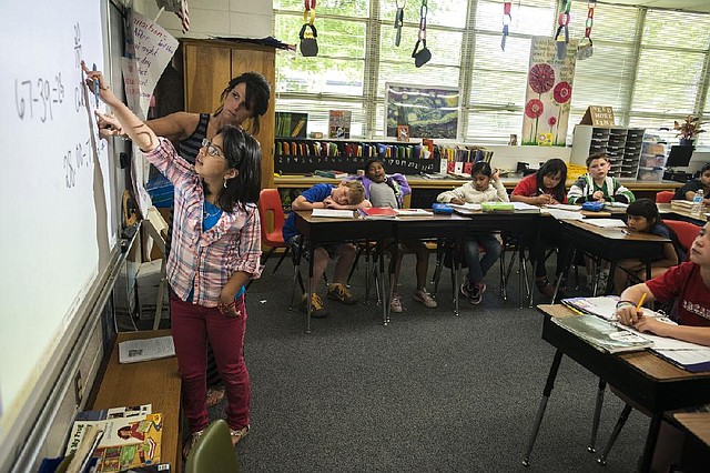 Ashley Violantes, 10, talks about how she solved a math problem Tuesday in Dawn Buchanan’s fourth-grade class at Elmdale Elementary in Springdale. Ashley and the rest of the class were using extended children’s mathematics to solve math problems. The students are allowed to solve a problem any way they can but must show their work and explain it to the class. 