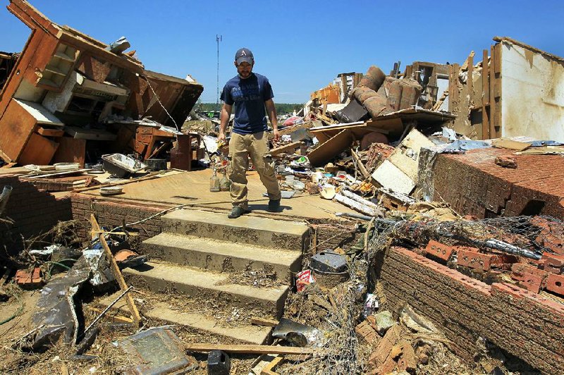 John King helps clean up Tuesday at his uncle’s home off Main Street in Vilonia. King said a gasoline tanker truck was blown through the house like a missile, narrowly missing Jim Purvis and Jim Purvis Sr. 