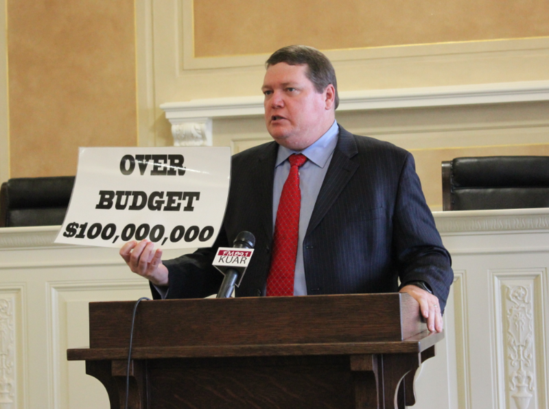 Sen. Bryan King, R-Green Forest, holds up a sign critical of the costs of the state's private option Medicaid expansion while speaking at a news conference Thursday.