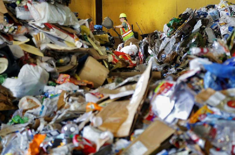 Arkansas Democrat-Gazette/JOHN SYKES JR. - A huge pile of waster frames Sheila Walker while she sorts at Waste Management's Materials Recovery Center on Sloan Drive in the Little Rock Port.