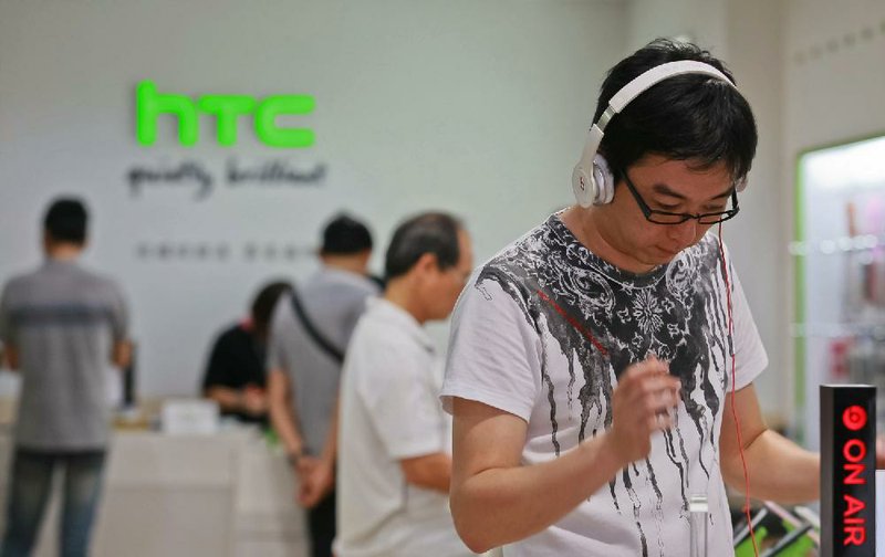 A customer tries out a HTC Corp. One X+ smartphone with a pair of Beats Electronics LLC headphones at one of the company's stores in Taipei, Taiwan, on Thursday, July 4, 2013. HTC is scheduled to announce second quarter earnings on July 8. Photographer: Maurice Tsai/Bloomberg