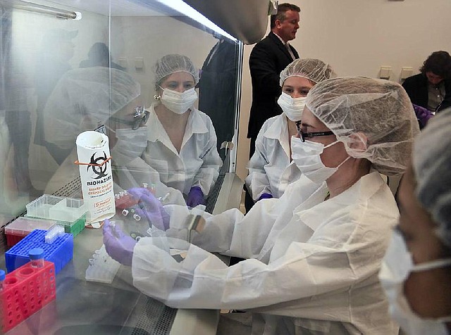 In this April 15, 2014 photo, Mark Desire, left, assistant director for forensic biology at the Office of Chief Medical Examiner, visits as criminalist trainees as they prepare sample bone fragments for DNA testing at the training lab in New York. With new technology yielding results impossible a dozen years ago, forensic scientists are still trying to match the bone with DNA from those who died on Sept. 11, 2001, and have never been identified. (AP Photo/Bebeto Matthews)