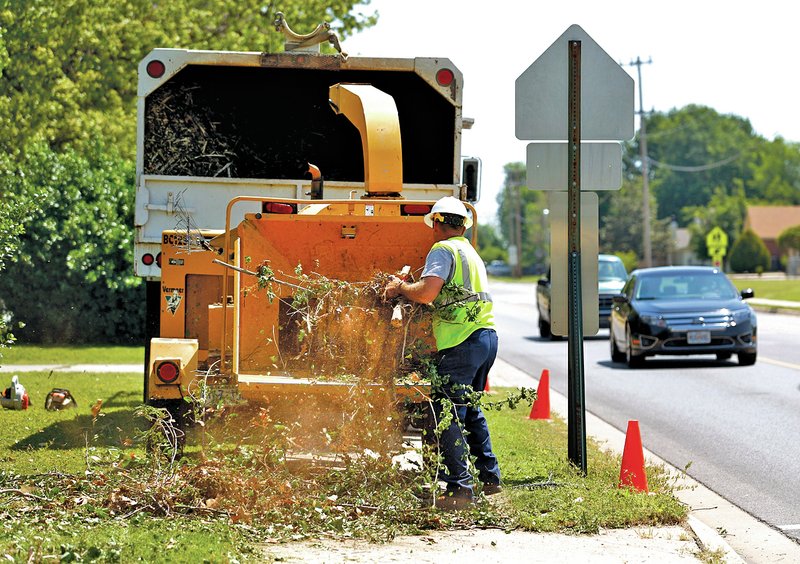 STAFF PHOTO JASON IVESTER Danny Stevens with Carroll Electric Cooperative loads tree branches into a mulcher to recycle on Wednesday along Olive Street in Rogers. A crew from Carroll Electric was trimming trees near power lines in the area.