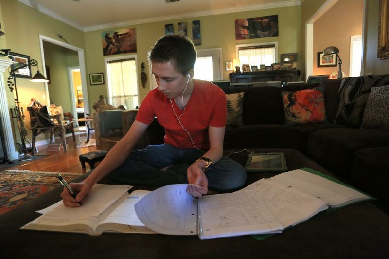 Arkansas Democrat-Gazette/RICK MCFARLAND --04/22/14--  Liam Gunter, 18, works on his studies atop a large ottoman, his usual spot, in his Russellville home on Tuesday. Liam, a home-schooled student scored perfect on his SAT and ACT tests.