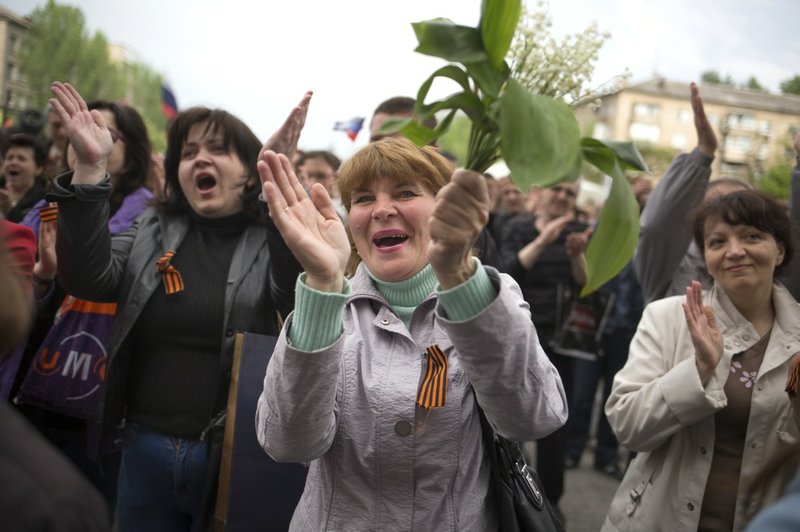Pro-Russian people applaud insurgent leader Denis Pushilin after his speech at barricades in front of a regional administration building that was seized by pro-Russian activists in Donetsk, eastern Ukraine, on Monday, May 12, 2014. 