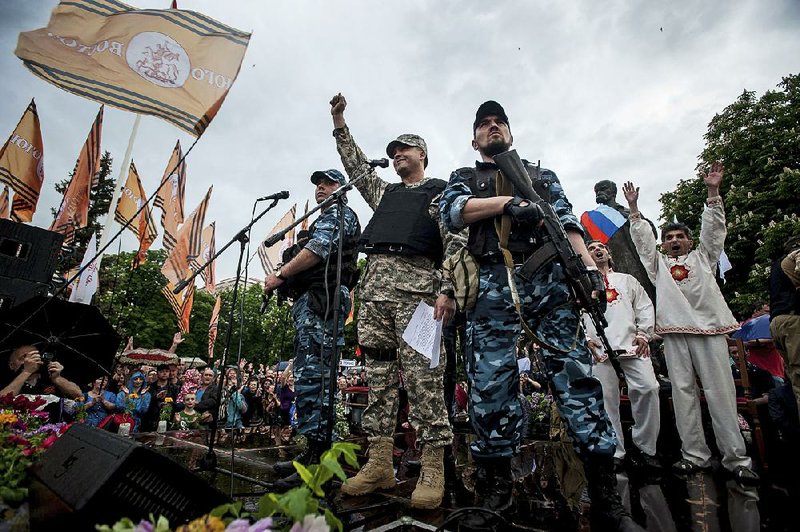 Pro-Russian gunmen and activists react while listening to a speaker as they declare independence for the Luhansk region in eastern Ukraine on Monday, May 12, 2014. Pro-Russia separatists in eastern Ukraine declared independence Monday for the Donetsk and Luhansk regions following their contentious referendum ballot. (AP Photo/Evgeniy Maloletka)