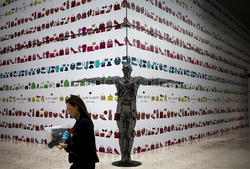 A woman walks past an art sculpture on display in front of an under construction fashion boutique outlet covered by its advertisement board at a shopping mall in Beijing, China Monday, May 12, 2014. Chinese president Xi Jinping has told the country to get used to slower growth, damping expectations of a new stimulus, following weakening trade and manufacturing. Economic growth slowed in the latest quarter to 7.4 percent after last year's full-year expansion of 7.7 percent tied 2012 for the weakest performance since 1999. (AP Photo/Andy Wong)