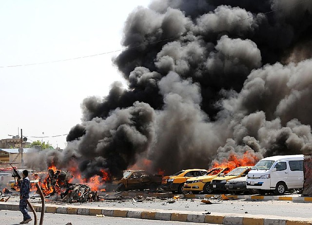 An Iraqi policeman stands near burning vehicles moments after one in a series of car bombs hit the Shiite stronghold of Sadr City in Baghdad, Iraq, on Tuesday. 