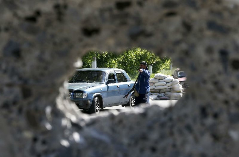 An armed pro-Russia militiaman checks a car Tuesday at the barricades on a road leading into Slovyansk in eastern Ukraine. 