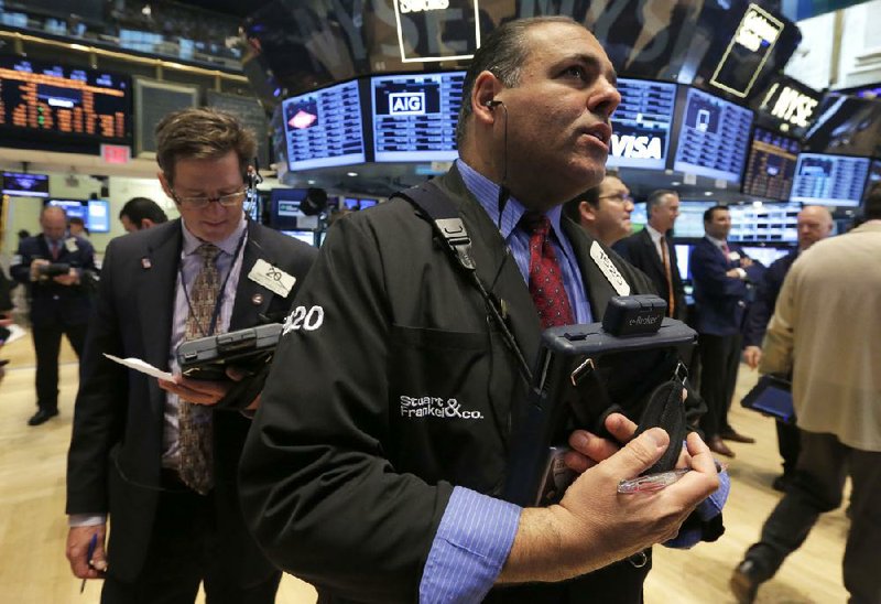 Trader Anthony Riccio (front) works Tuesday on the floor of the New York Stock Exchange where the Standard & Poor’s 500 index surpassed 1,900.00 during the trading session for the first time.