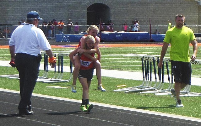 Claire Gruenke, an eighth-grade student in Trenton, Ill., carries her twin sister, Chloe, to the finish line in an 800-meter run during a junior high state meet in Carterville, Ill. 