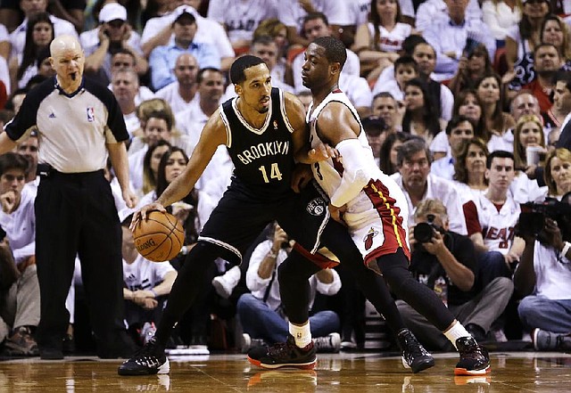 Miami Heat guard Dwyane Wade (right) pressures Brooklyn Nets guard Shaun Livingston during Wednesday night’s NBA playoff game in Miami. Wade scored 28 points as the Heat won 96-94 to win the series. 