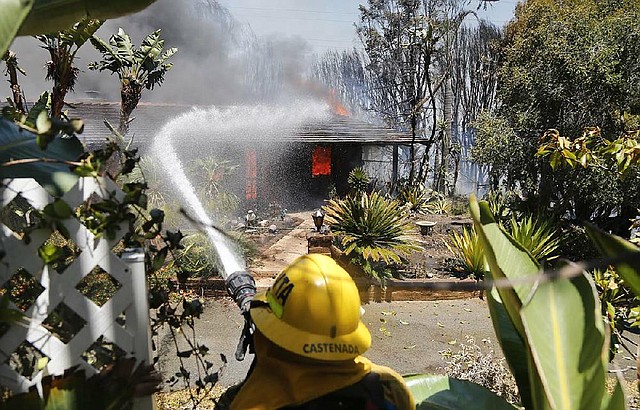 A firefighter directs water onto a burning home Wednesday in Carlsbad, Calif., where thousands have been forced to evacuate. 
