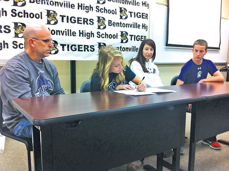 STAFF PHOTO HENRY APPLE Madison Sellars, second from left, of Bentonville signs her national letter of intent to run track and cross country at Central Arkansas during Wednesday&#8217;s ceremony at the Tiger Athletic Complex. She is joined by her father Mike Sellars, from left, her mother Kirstin Sellars and her brother Nathan Sellars.