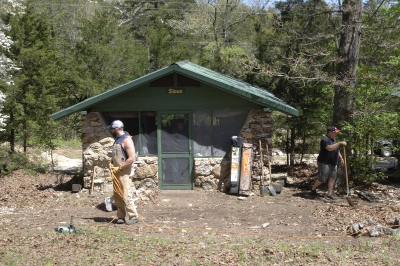 Workers spruce up near one of the cabins at Old Kia Kima on the Spring River near Hardy. Former campers have banded together to restore the camp. It is open and available for use by youth groups at no charge.