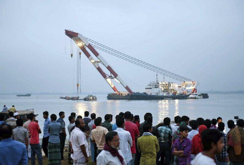 Relatives wait on the banks of the Meghna River as rescuers try to tow the ferry that capsized Friday in Munshiganj, Bangladesh. 