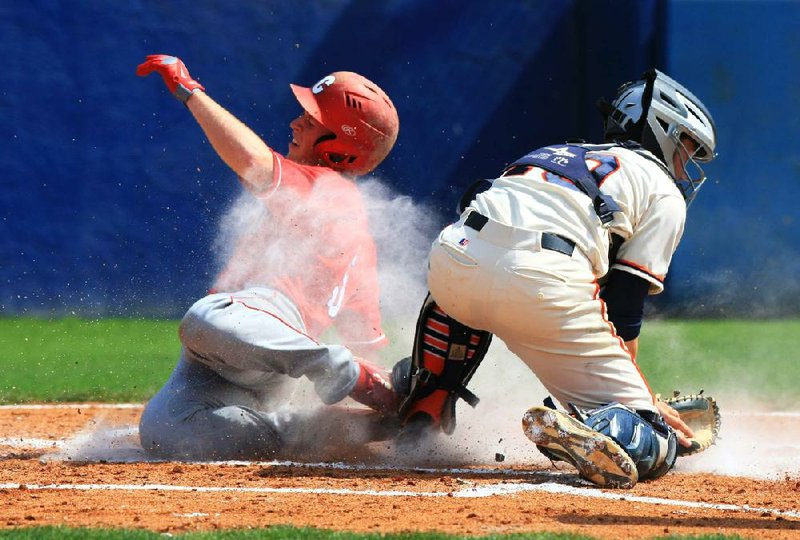 Cabot’s Grayson Cole (left) slides home safely to score the Panthers’ first run in a 4-1 victory over Rogers Heritage in the Class 7A state baseball tournament at Burns Park in North Little Rock. Heritage catcher Brandon Norris takes the throw, but it came too late to make the tag. 