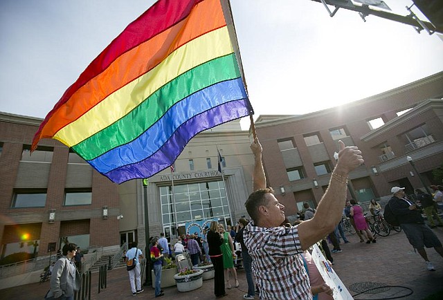 Carmine Caruso holds a rainbow flag during a rally in supports of same sex marriage in front of the Ada County courthouse in Boise, Idaho, on Friday, May 16, 2014.  Idaho's gay marriage ban was overturned Tuesday when U.S. District Judge Candy Dale said the law unconstitutionally denied gay and lesbian residents their fundamental right to marry.  On May 15, 2014, a three-judge panel of the 9th U.S. Circuit Court of Appeals issued a temporary stay while it considers whether a longer stay is needed. (AP Photo/The Idaho Statesman, Kyle Green)  LOCAL TV OUT  