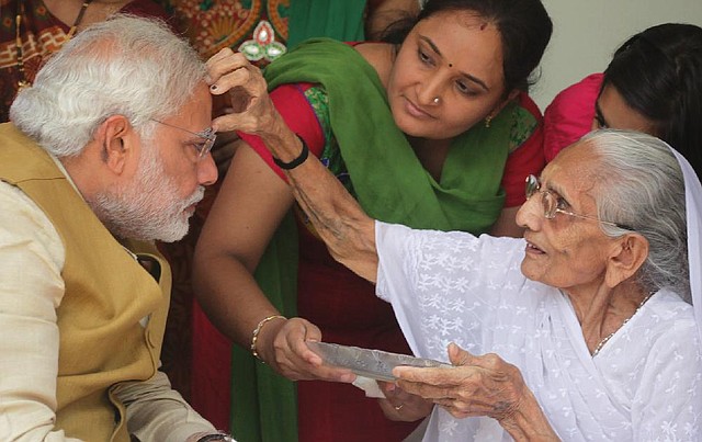 90-year-old Hiraben marks the forehead of her son and India's next prime minister Narendra Modi with vermillion as a sign of blessing in Gandhinagar, in the western Indian state of Gujarat, Friday, May 16, 2014. The top official in Gujarat state for over a decade, Modi often contrasted his humble roots with the posh background of his main rival, 43-year-old Rahul Gandhi, heir to India's most powerful political dynasty. As the career politician led his party through a dazzling, high-tech election campaign, Modi called voters' attention to his mother riding a three-wheeled auto-rickshaw to cast her ballot earlier this month. "I am the chief minister of a prosperous state ... And my 90-year-old mother goes to vote in an auto-rickshaw," the white-bearded Modi boasted, punching a fist through the air as he claimed his place by India's poor masses. (AP Photo/Ajit Solanki)