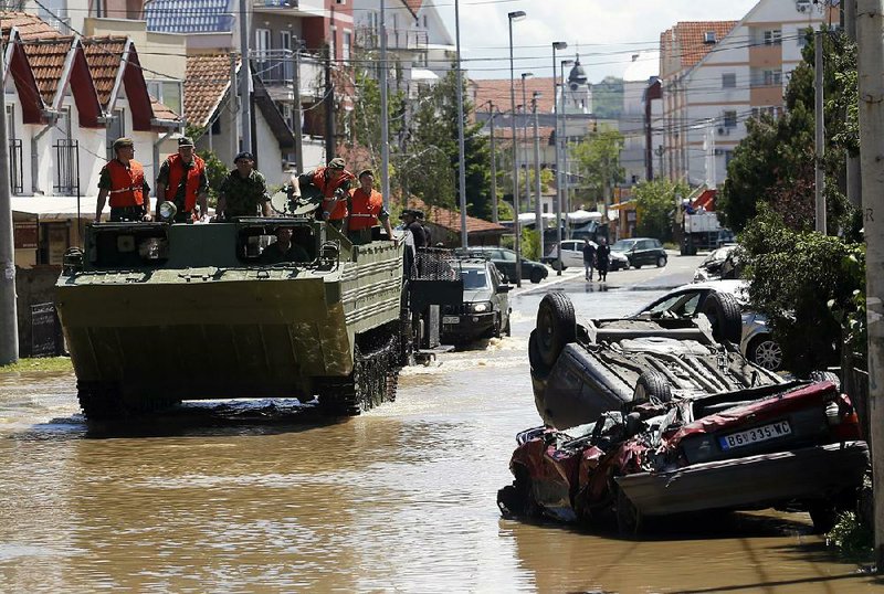 A military amphibious vehicle drives through street where flood waters are retreating in Obrenovac, some 30 kilometers (18 miles) southwest of Belgrade, Serbia, Monday, May 19, 2014. Belgrade braced for a river surge Monday that threatened to inundate Serbia's main power plant and cause major power cuts in the crisis-stricken country as the Balkans struggle with the consequences of the worst flooding in southeastern Europe in more than a century. At least 35 people have died in Serbia and Bosnia in the five days of flooding caused by unprecedented torrential rain, laying waste to entire towns and villages and sending tens of thousands of people out of their homes, authorities said. (AP Photo/Darko Vojinovic)