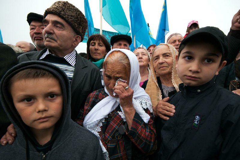 An elderly woman cries as she and other Crimean Tatars rally in Simferopol, Crimea, Sunday, May 18, 2014. Crimean Tatars gathered for a rally commemorating the 70th anniversary of Stalin's mass deportation. (AP Photo/Alexander Polegenko)