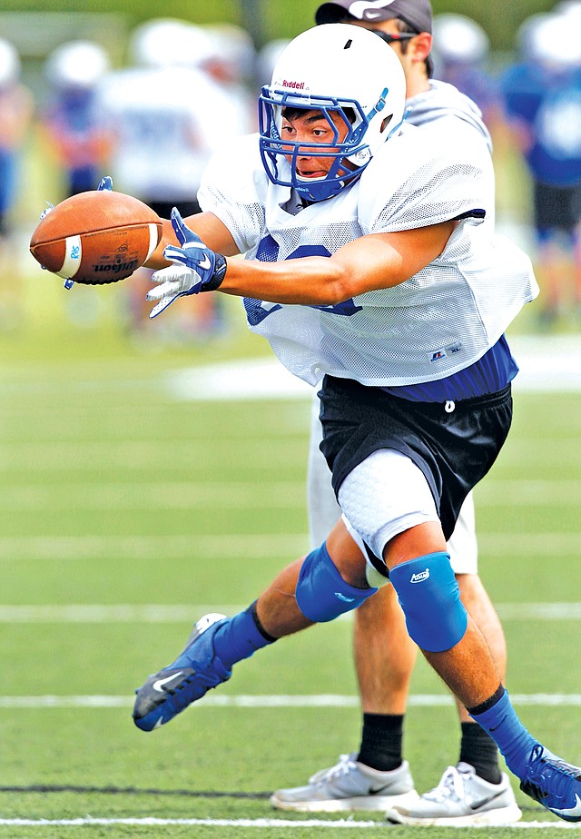 STAFF PHOTO JASON IVESTER Justice Thompson, Rogers High running back, reaches for the ball during practice Thursday in Rogers.