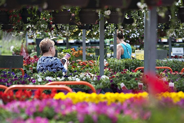 Customers look at plants in the garden center of a Home Depot store in Peoria, Ill., on Monday. Home Depot on Tuesday reported a fi rst-quarter profit of $1.38 billion. 