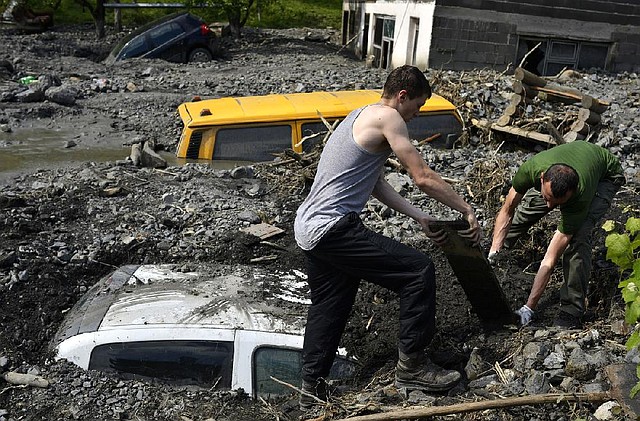 Residents try to excavate a car trapped in the mud caused by a landslide at the village of Topcic Polje, near the town of Zenica, Bosnia-Herzegovina, on Tuesday. Bosnia, Serbia and Croatia have been hit by the worst flooding in more than 100 years, forcing half a million people out of their homes and leading to more than three dozen deaths. 