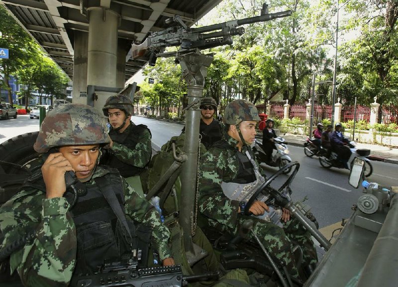 Motorcyclists pass Thai soldiers stationed outside the Thai police headquarters on Tuesday in Bangkok. 