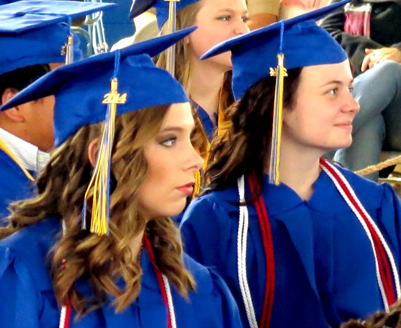 Brittany Frost and Brittanie Libberton watch intently on a video presentation during the 2014 Decatur High School graduation ceremony May 17. The presentation spotlighted a few photos of each senior as they progressed from childhood into adulthood.