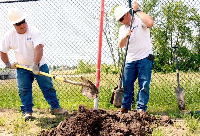 Jeff Della Rosa/Herald-Leader Derek Ferguson and Foy Palmore, both with Siloam Springs Electric Department, dig up soil in order to install an electrical box for wiring near the east field at Sager Creek Soccer Complex on Tuesday. The fields should be ready for play this fall.