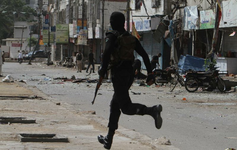 A Pakistani police commando rushes to the site of an explosion Wednesday in Karachi in which a bomb had been rigged to a motorcycle and exploded outside a paramilitary office. 