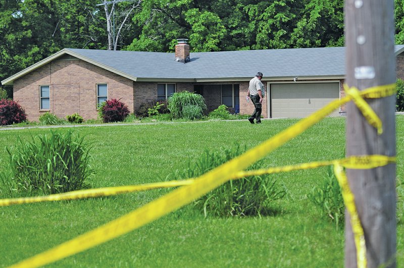 Staff Photo Spencer Tirey A Washington County Sheriff&#8217;s Office deputy walks near the front of 579 Story Lane near Tontitown where a person was stabbed and killed Wednesday. Deputies place crime tape across Story Lane Road blocking traffic and across the front of the house.