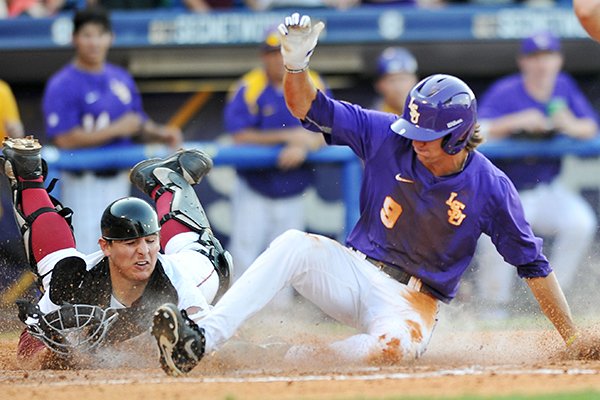 LSU base runner Mark Laird slides across home plate ahead of the tag from Arkansas catcher Alex Gosser during the seventh inning of a SEC Tournament game on Thursday, May 22, 2014 at Hoover Metropolitan Stadium in Hoover, Ala. 