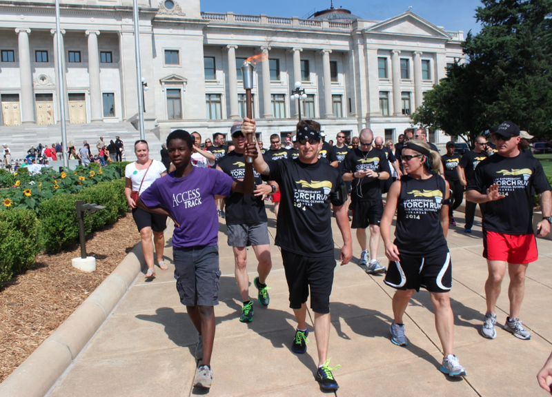 Special Olympics athlete Eli Falls, 15, left, helps escort the 2014 Special Olympics Arkansas Summer Games torch from the Arkansas state Capitol Thursday.