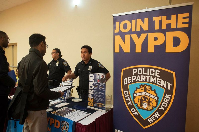 Kim Thy of the New York City Police Department (NYPD), right, speaks with job seeker Eric Swasey of Manhattan at Choice Career Fairs' New York career fair at the Holiday Inn Midtown in New York, U.S., on Tuesday, May 13, 2014. The U.S. Department of Labor is scheduled to release initial and continuing jobless claims data on May 15. Photographer: Craig Warga/Bloomberg *** Local Caption *** Kim Thy; Eric Swasey