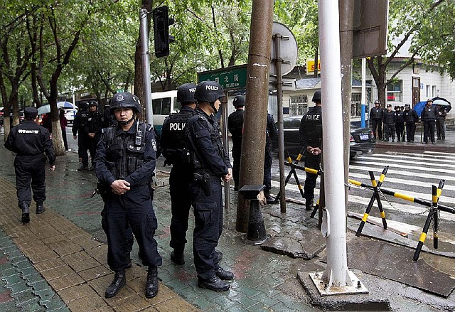 Armed policemen stand guard near the site of an explosion in Urumqi, northwest China's Xinjiang region, Thursday, May 22, 2014. Assailants in two SUVs plowed through shoppers while setting off explosives on a busy street market in China's volatile northwestern region of Xinjiang on Thursday, the local officials said, killing over two dozen people and injuring more than 90. The attack in the city of Urumqi was the bloodiest in a series of violent incidents that Chinese authorities have blamed on radical separatists from the country's Muslim Uighur minority.   (AP Photo/Andy Wong)